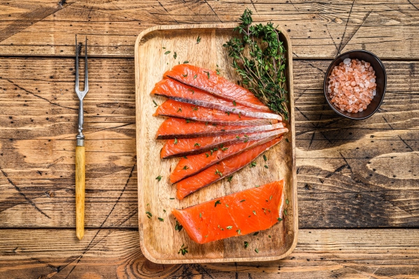 salted salmon fillet slices in a wooden tray with thyme - Мини-бутерброды с лососем