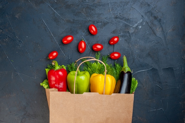 top view colorful bell peppers aubergine greens in paper bag cherry tomatoes on dark background - Овощная пицца