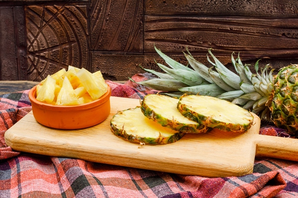 Пикантная закуска из ананаса whole sliced pineapple cutting board clay bowl stone tile picnic cloth side view - Пикантная закуска из ананаса