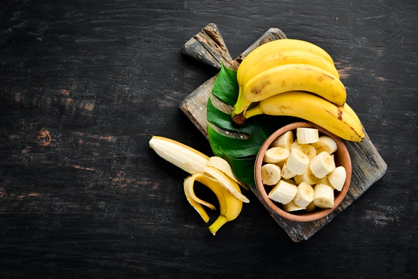 bananas on a black wooden surface tropical fruits top view free copy space - Молочно-фруктовый смузи с овсянкой