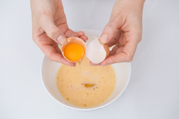 close up of woman separating egg at kitchen table - Французские тосты с яйцом