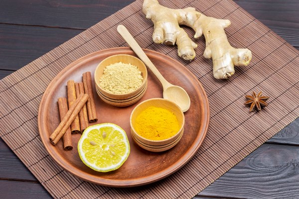 dry ginger and turmeric powder in bowls cinnamon sticks and lemon on ceramic plate ginger root on table dark wooden background top view - Безалкогольный вишнёво-ванильный глинтвейн