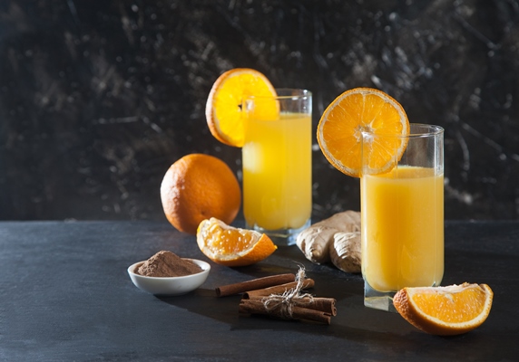 ginger orange drink in glass glasses orange ginger and cinnamon on a black background detox fresh juice - Безалкогольный апельсиновый глинтвейн с имбирём