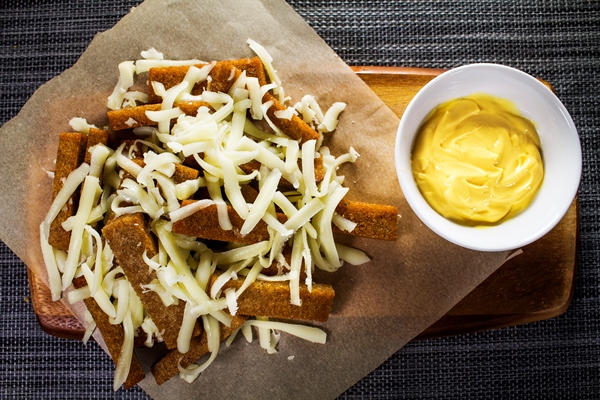 topped rye bread croutons sprinkled with grated cheese and sauce on a wooden plate - Бульон "борщок"