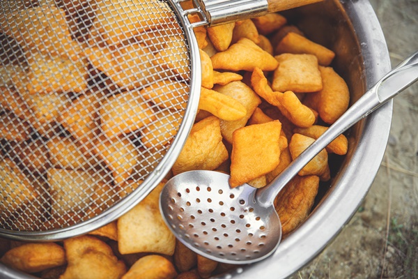 traditional kazakh and central asian fresh baursaks in a large dish with a colander and slotted spoon - Баурсаки