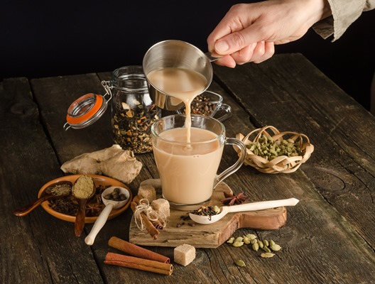 woman pours masala tea with spices a warming drink from india - Чай масала