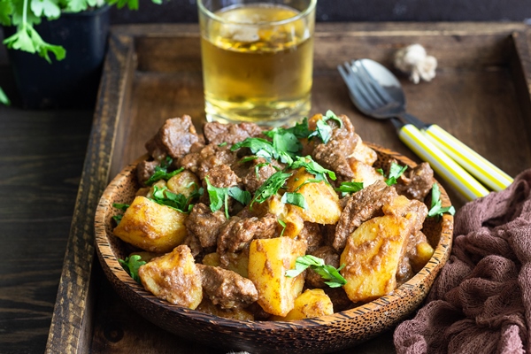 meat stew with potatoes and parsley in wooden dish traditional portuguese meat stew 1 - Тушёная говядина с картофелем и луком