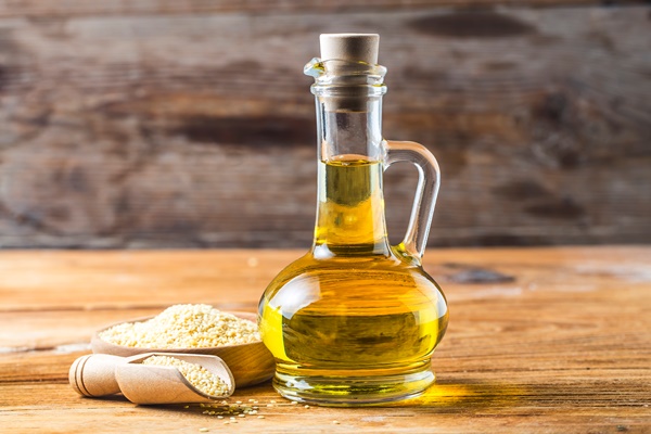 sesame seeds and bottle with oil on a old wooden table sesame oil oil in a glass jug - Постный томатный соус