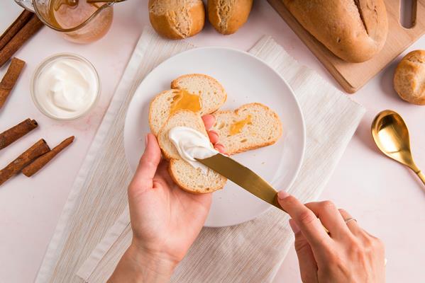 top view woman spreading cream cheese bread - Правила подачи сыров