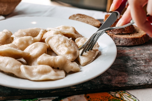 a front view dough meal with minced meat inside salted peppered eastern dish along with bread loafs cuisine meat on the brown wooden desk - Монастырская кухня: грибные вареники, овсяный кисель