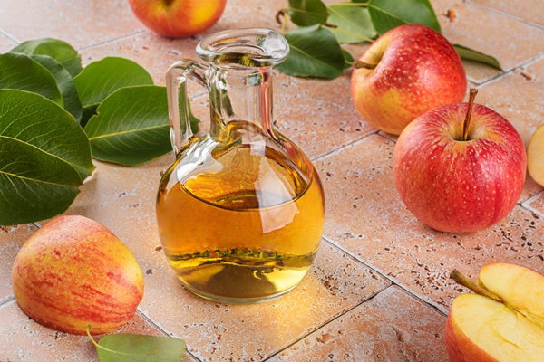 apple cider vinegar of fermented fruit in glass bottle with apples on beige travertine tiles table background - Соус с хреном для отварного языка и мяса