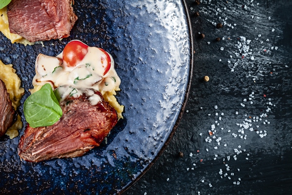 close up view on juicy medium roast beef steak sliced with blood served on dark plate with tomato and mashed potato meat food american food copy space for design - Соус майонез с корнишонами