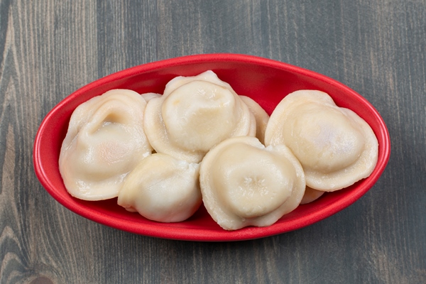 delicious dumplings in a red plate on a wooden table - Монастырская кухня: вареники с яблоком и изюмом