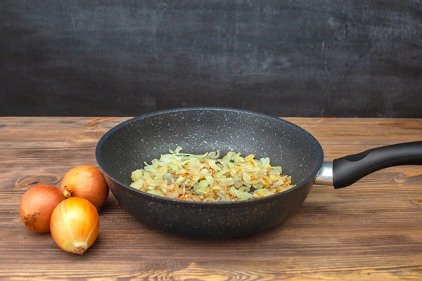 frying pan with fried onions three onions side by side chalk board in the background - Мясо в сметане