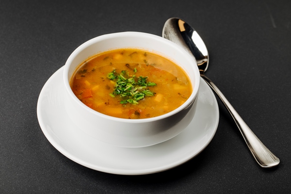 lentil soup with mixed ingredients and herbs in a white bowl with a spoon - Монастырская кухня: густой суп из чечевицы и тыквы, лепёшки с зеленым луком