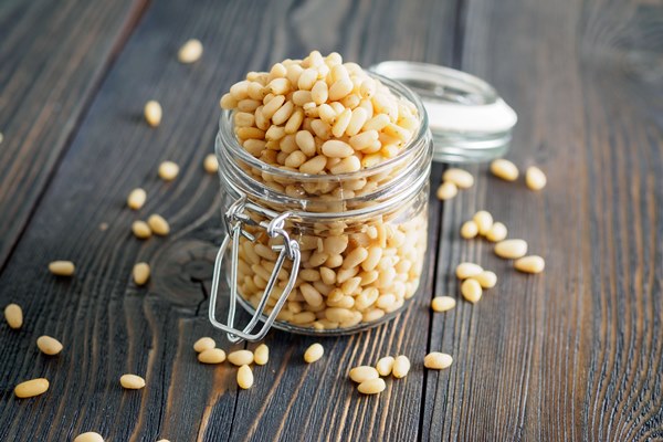 Урбеч из кедровых орешков side view of glass jar with a handful of pine nut cedar nuts on a wooden background - Урбеч из кедровых орешков