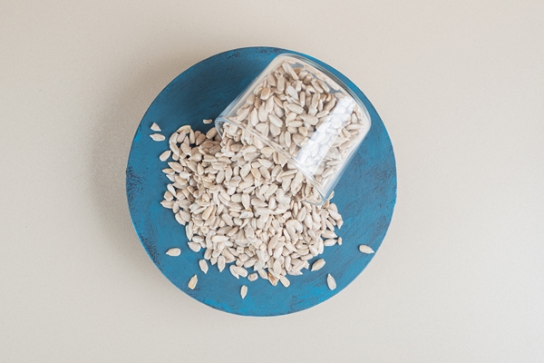 sunflower seeds out of a glass cup on a blue board - Закусочная медово-подсолнечная паста