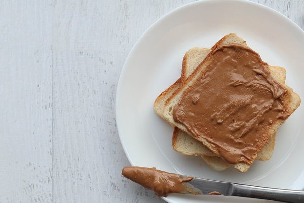 Урбеч из грецких орехов закусочный toast with peanut paste on a white surface - Урбеч из грецких орехов закусочный