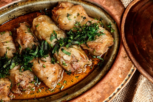 top view cabbage rolls with herbs and tomatoes on the table - Голубцы мясные