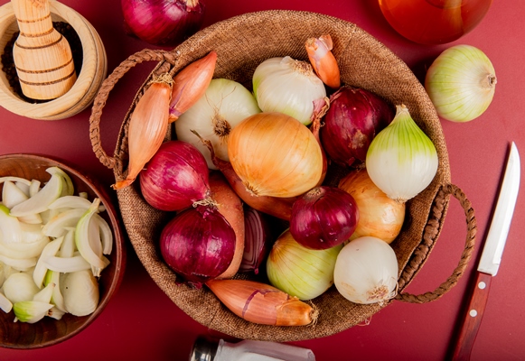 top view of onions in basket with black pepper sliced onion in bowl salt butter and knife around on red - Монастырская кухня: густой суп из чечевицы и тыквы, лепёшки с зеленым луком