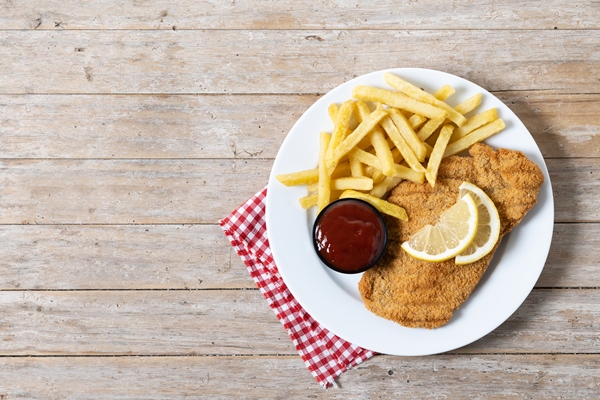 Шницель wiener schnitzel with fried potatoes on wooedn table - Шницель