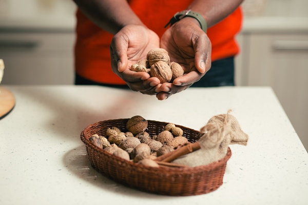 close up of the wicker basket with cinnamon and walnuts on the table and hands of man holding walnuts - Австрийский пасхальный рулет