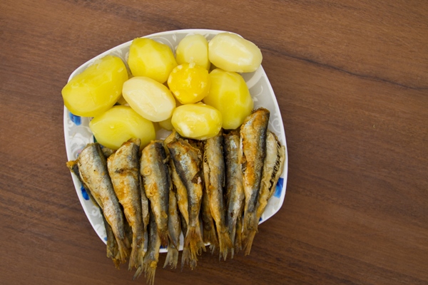 Салака в крахмальной панировке fried baltic herring with boiled potatoes on a plate on wooden background - Салака в крахмальной панировке