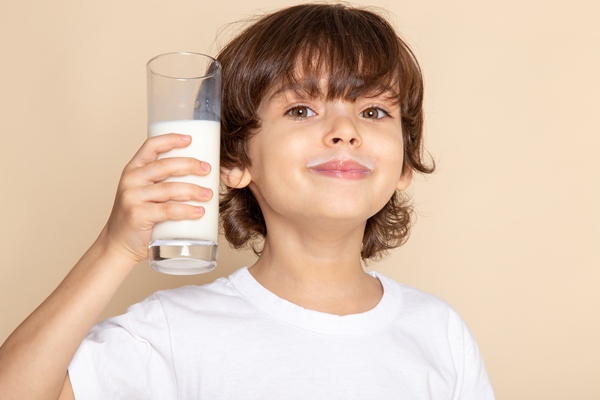 Особенности питания детей little kid adorable drinking whole white milk smiling on pink - Особенности питания детей