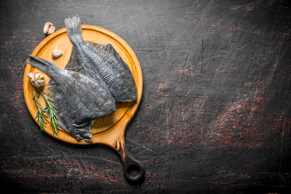 raw fish flounder on wooden cutting board with garlic and rosemary on dark rustic table 1 - Камбала, запечённая с шалфеем