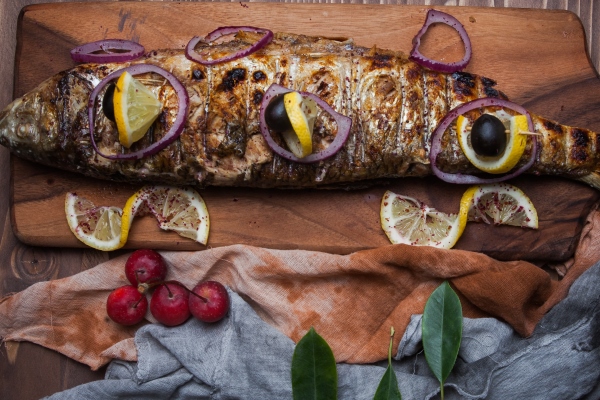 Скумбрия, запечённая с яблоками top view fried fish with lemon and paradise apples and onion in cutting board - Скумбрия, запечённая с яблоками