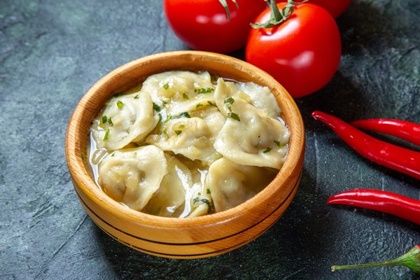 front view yummy meat dumplings inside wooden plate with fresh tomatoes on dark surface - Пельмени с кислицей