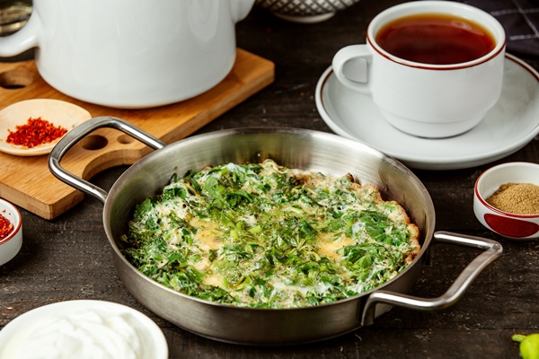 side view of azerbaijani traditional kuku fried eggs with herbs in pan - Омлет со снытью