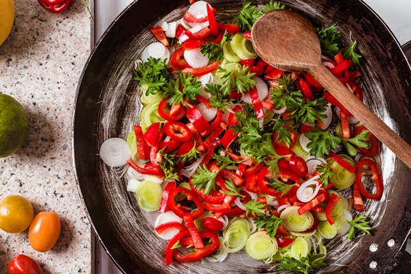 top view of the mix of fresh vegetables in the rustic pan with a wooden spoon - Острый рыбный суп с томатом