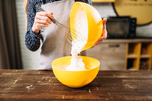 female person in apron prepares cream for the cake on wooden table - Кулич бабушкин