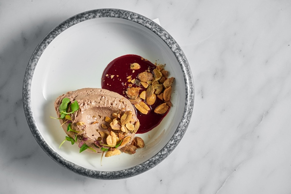 restaurant pate with berry sauce peanuts and microgrin in a marble plate with toast in a metal basket on white marble - Соус из красной смородины