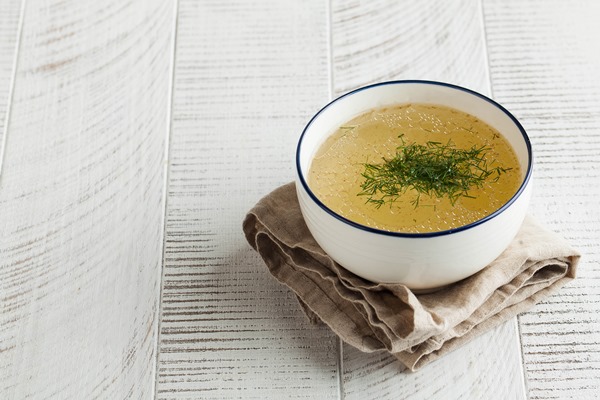 homemade bone broth in a white bowl on a wooden table the concept of healthy eating copy space - Суп из баранины с помидорами в горшочке