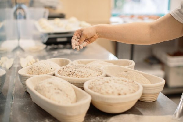 baker woman sprinkles flour on the shaped loaves rustic style bread before baking rustic whole grain bread 8544 3132 - Ржаной хлеб