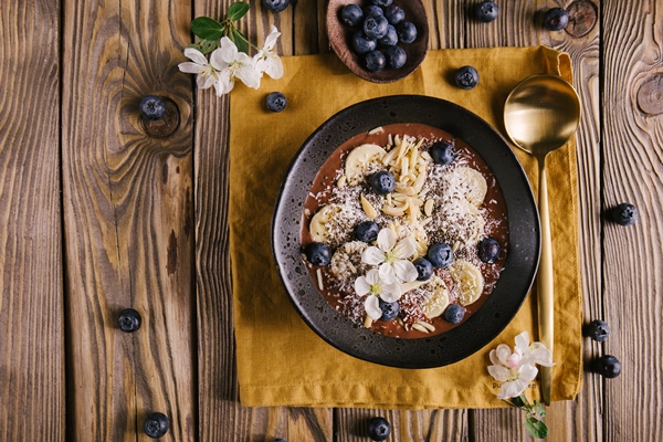 Постный смузи-боул с финиками и орехами smoothie bowl on white plate on wooden table - Постный смузи-боул с финиками и орехами