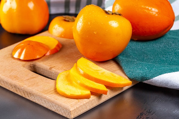 ripe juicy persimmons whole and chopped on a kitchen board - Смузи-боул с хурмой и семенами чиа