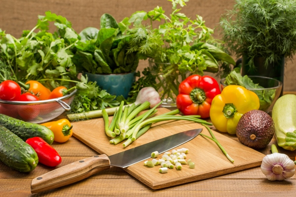 sliced green onions and a kitchen knife on cutting board vegetables and greens on table wooden background - Овощной салат с киноа