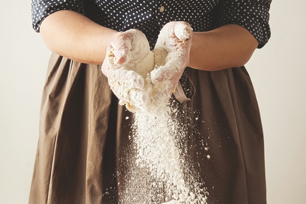 woman adds some flour to dough on wooden table near knife two rolling pins measure cup transparent jae with flour and olive oil bottle step by step cooking pasta dumplings guide - Драники с апельсиново-клюквенным соусом