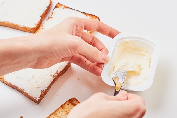Консервирование пищевых продуктов woman hand make sandwich spred toasted bread with a cheese - Консервирование пищевых продуктов
