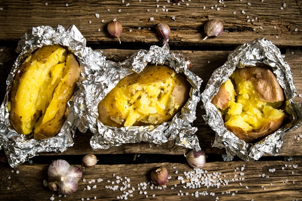 Печёный на углях картофель с начинкой baked potatoes in foil on a wooden table 1 - Печёный на углях картофель с начинкой
