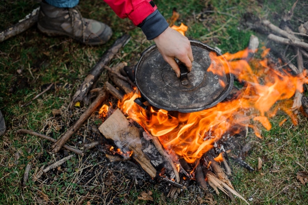 boy placing a cover on the black pan standing on the bonfire in winter in the forest - Омлет "Туристический"