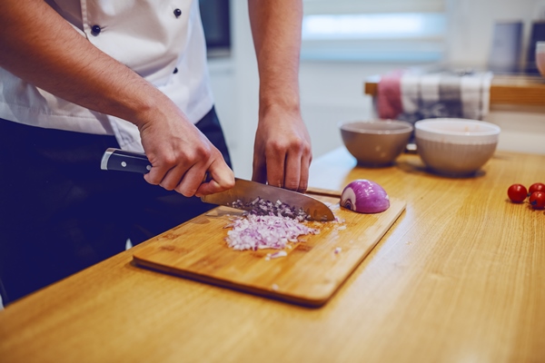 caucasian chef in uniform standing at domestic kitchen and chopping onion - Тюря