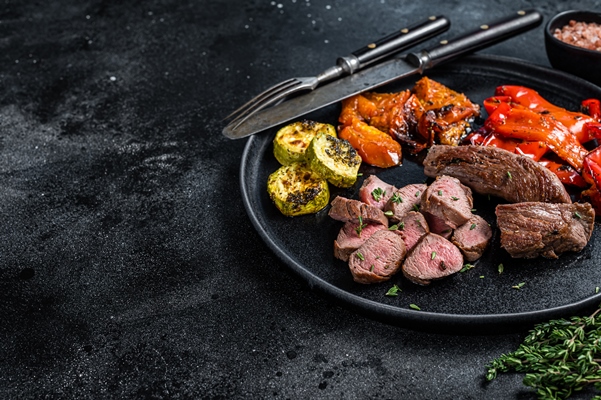 Жаркое из косули roasted lamb or goat tenderloin meat steak in plate with grilled vegetables - Жаркое из косули
