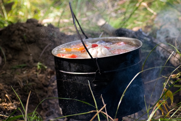 a hunter cooks shurpa in a bowler hat on the fire in nature - Шурпа "Туристическая"