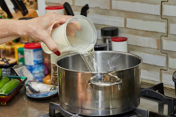 Старинные секреты приготовления мясных бульонов chef pours water from measuring cup into pot ongas stove - Старинные секреты приготовления мясных бульонов