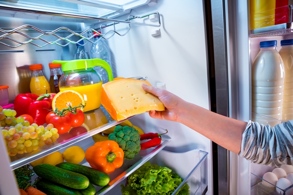 Кулинарные секреты для одиноких woman takes the piece of cheese from the open refrigerator - Кулинарные секреты для одиноких