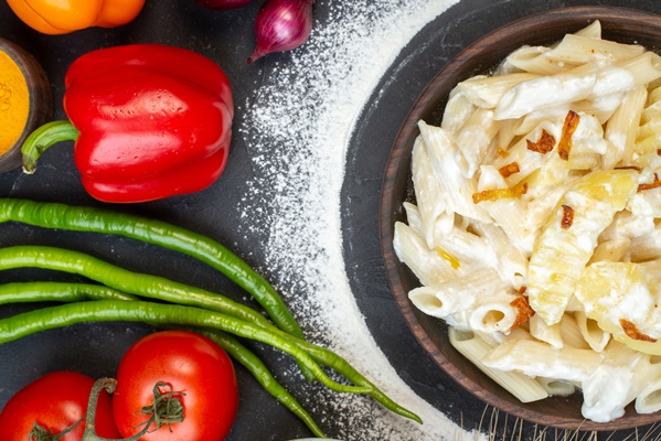 top view tasty penne pasta with potato in bowl bell peppers green long hot peppers tomatoes on table - Разварной картофель с жареным луком и макаронами